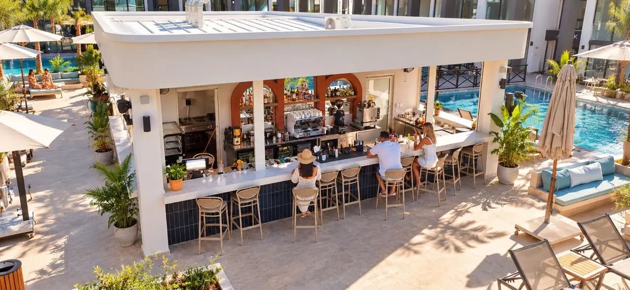 Joy Cafe'nin açık hava barı, kahve tezgâhı ve havuz çevresindeki oturma alanı.